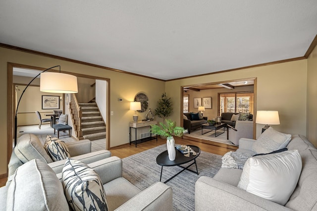 living area featuring crown molding, stairs, baseboards, and wood finished floors