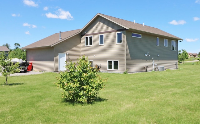 back of house with central AC unit and a yard