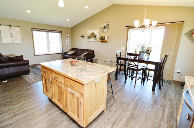 kitchen featuring pendant lighting, vaulted ceiling, light hardwood / wood-style flooring, light brown cabinetry, and a kitchen island