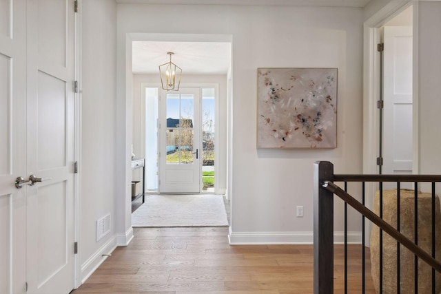 foyer entrance with wood-type flooring and a chandelier