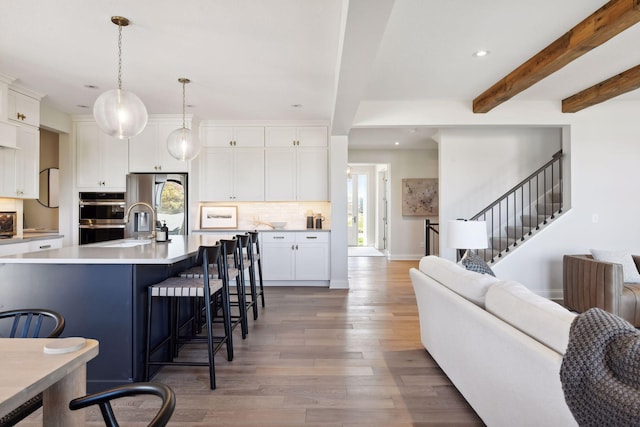 kitchen with a wealth of natural light, beam ceiling, hanging light fixtures, and hardwood / wood-style flooring