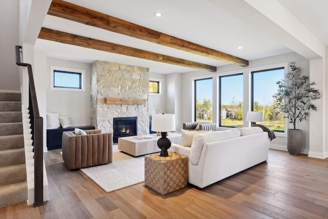 living room with a stone fireplace, hardwood / wood-style floors, and beam ceiling