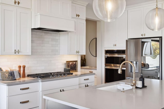 kitchen featuring decorative backsplash, sink, white cabinetry, and hanging light fixtures