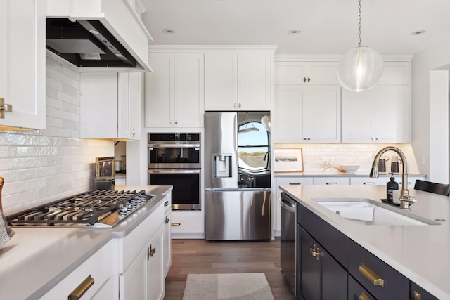 kitchen with appliances with stainless steel finishes, premium range hood, white cabinets, and hanging light fixtures