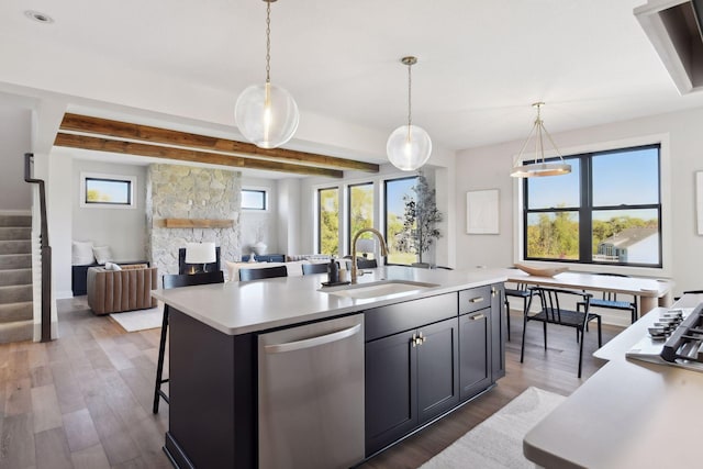 kitchen with dishwasher, sink, decorative light fixtures, dark hardwood / wood-style floors, and a kitchen island with sink