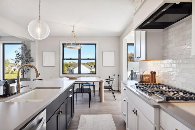 kitchen featuring hanging light fixtures, white cabinetry, stainless steel appliances, hardwood / wood-style flooring, and extractor fan