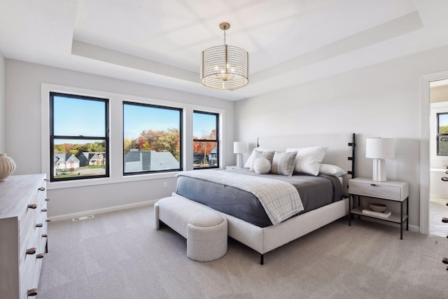 carpeted bedroom with a chandelier and a raised ceiling