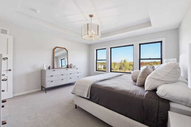 bedroom with a tray ceiling and light colored carpet