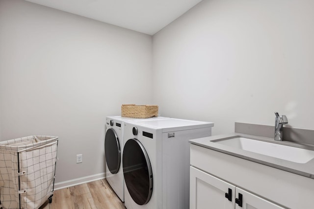 laundry room with sink, light hardwood / wood-style flooring, cabinets, and washer and clothes dryer