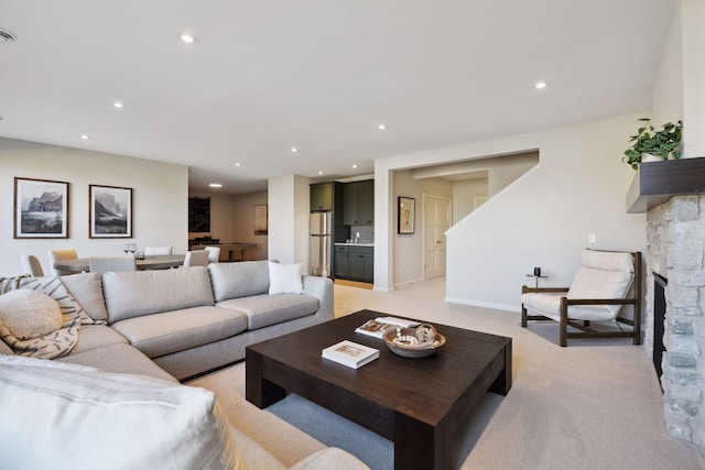 carpeted living room with a stone fireplace