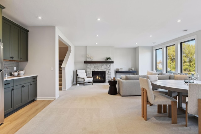 dining room featuring a stone fireplace and light hardwood / wood-style flooring