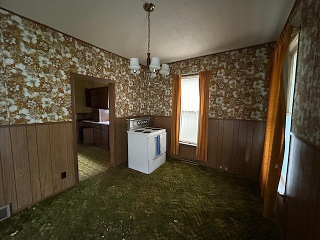 kitchen with wooden walls, washer and clothes dryer, and a notable chandelier