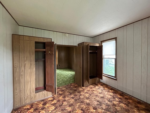 unfurnished bedroom with carpet flooring and wooden walls