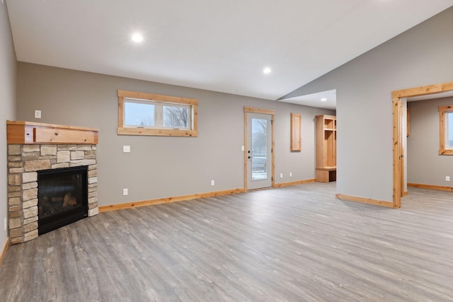 unfurnished living room featuring a fireplace, light wood-type flooring, and vaulted ceiling