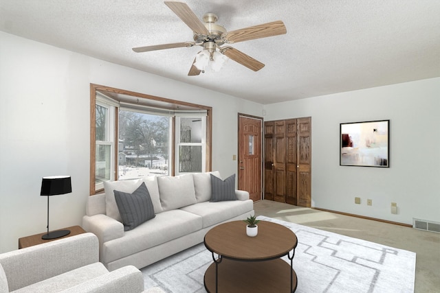 carpeted living room featuring ceiling fan and a textured ceiling