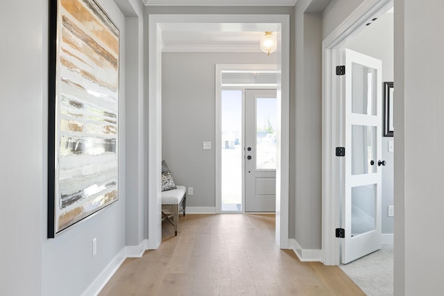 foyer with a wealth of natural light, light wood-type flooring, and ornamental molding