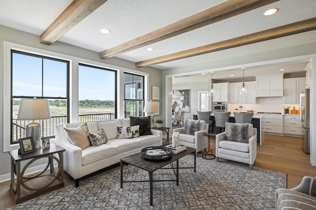 living room featuring plenty of natural light, dark wood-type flooring, a textured ceiling, and beam ceiling