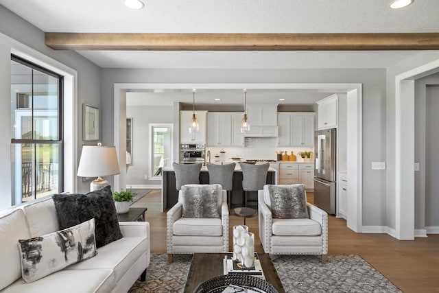 living room featuring sink, beam ceiling, and hardwood / wood-style floors