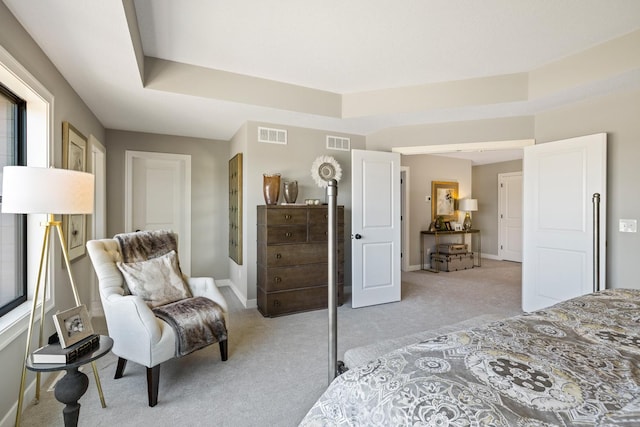 bedroom with light carpet and a tray ceiling