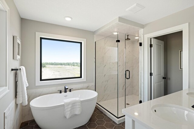 bathroom featuring tile walls, tile patterned floors, plus walk in shower, and vanity