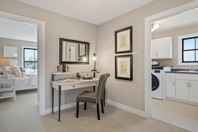 office space featuring washer / dryer, light carpet, and sink