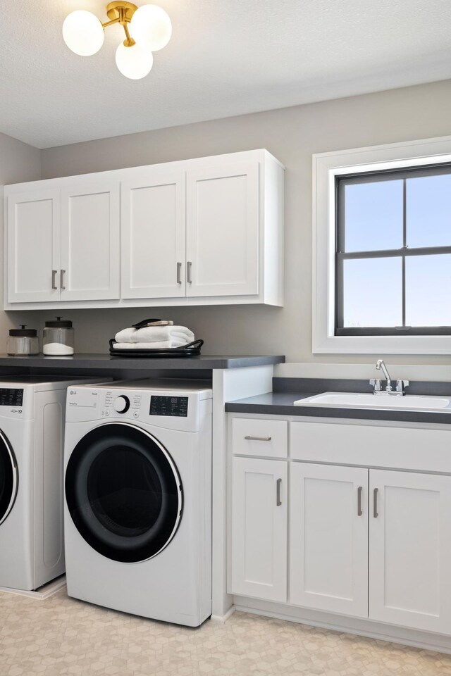 clothes washing area with cabinets, light tile patterned floors, washer and dryer, and sink