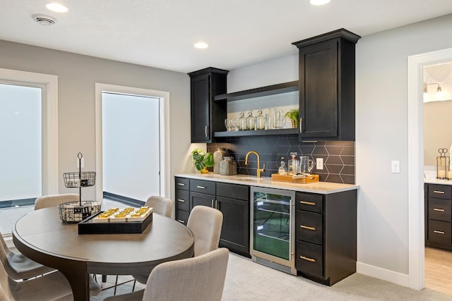 bar featuring sink, light hardwood / wood-style flooring, backsplash, and beverage cooler