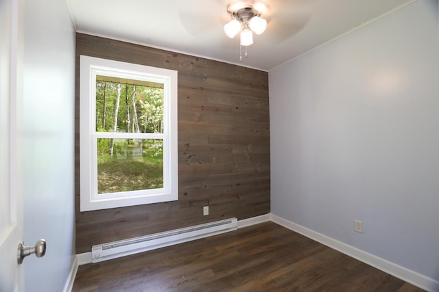 spare room with baseboards, dark wood finished floors, ceiling fan, wood walls, and a baseboard heating unit