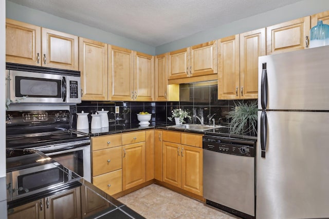 kitchen featuring a textured ceiling, sink, appliances with stainless steel finishes, and tasteful backsplash