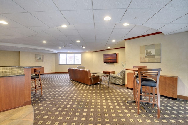 living room with carpet floors, a drop ceiling, and crown molding