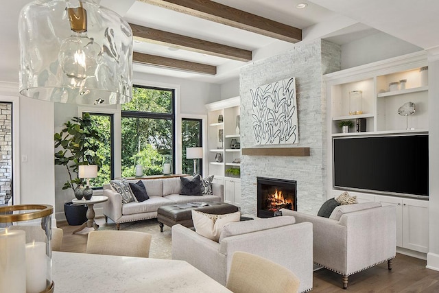 living room featuring built in features, beam ceiling, a stone fireplace, and hardwood / wood-style flooring