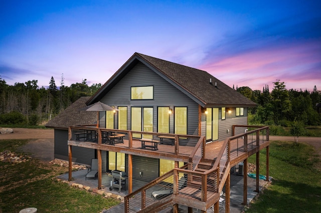 back house at dusk featuring a patio area and a wooden deck