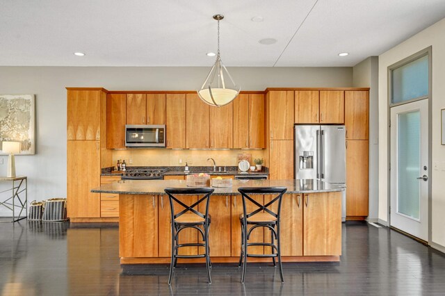 kitchen with a center island, dark hardwood / wood-style floors, a kitchen bar, hanging light fixtures, and appliances with stainless steel finishes