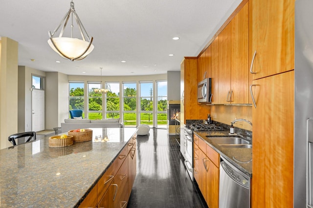 kitchen featuring pendant lighting, sink, dark wood-type flooring, appliances with stainless steel finishes, and dark stone counters