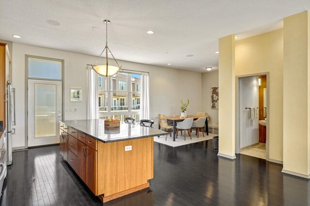 kitchen featuring dark hardwood / wood-style flooring, pendant lighting, a textured ceiling, stone counters, and a center island