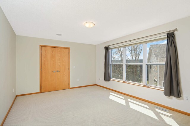 unfurnished bedroom with a closet and light colored carpet