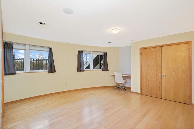 unfurnished bedroom featuring a closet, multiple windows, and light hardwood / wood-style flooring