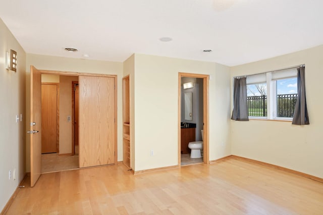 unfurnished bedroom featuring hardwood / wood-style flooring, a closet, and ensuite bath