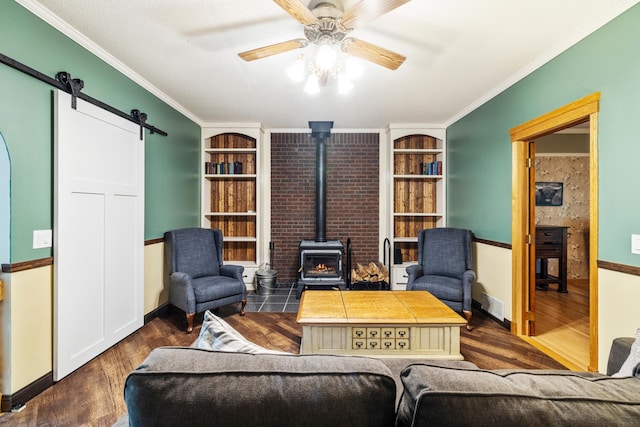 living room with a wood stove, a barn door, dark hardwood / wood-style flooring, and ceiling fan