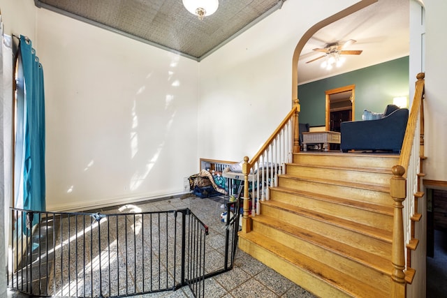 stairway with ornamental molding, ceiling fan, and tile patterned floors