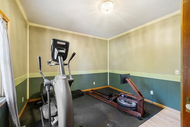 exercise area with a textured ceiling, wood-type flooring, and ornamental molding