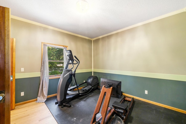 workout area with a textured ceiling, wood-type flooring, and ornamental molding