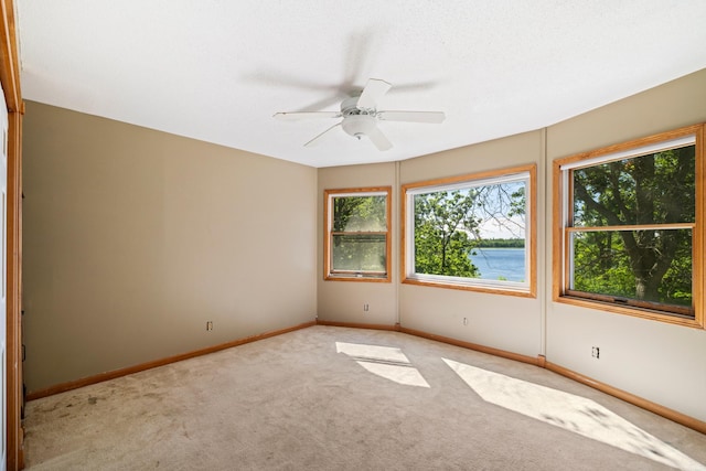 spare room featuring a water view, carpet, and ceiling fan