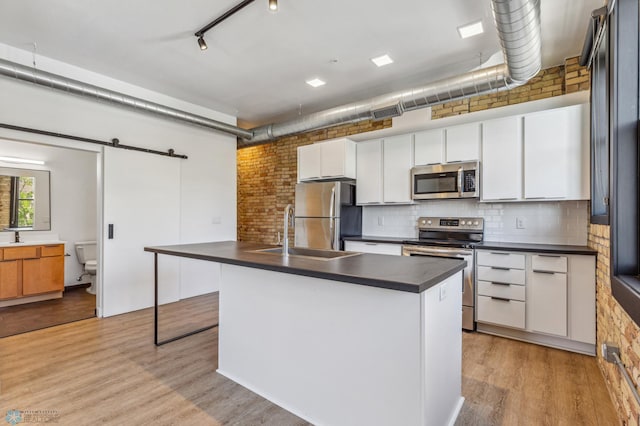 kitchen featuring white cabinets, light hardwood / wood-style floors, a barn door, and stainless steel appliances