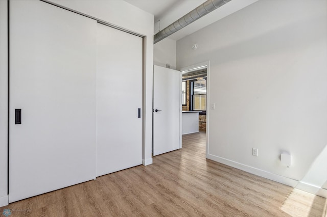 unfurnished bedroom with a closet and light hardwood / wood-style flooring