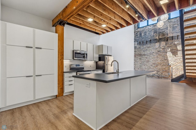 kitchen with sink, light hardwood / wood-style floors, a kitchen island with sink, white cabinets, and appliances with stainless steel finishes