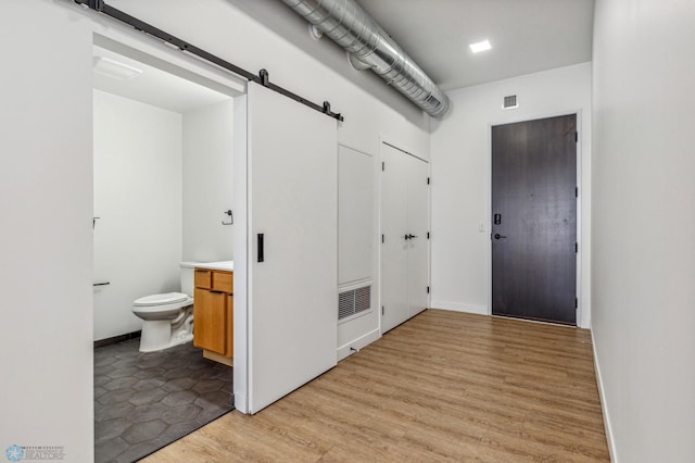 corridor featuring a barn door and light hardwood / wood-style flooring