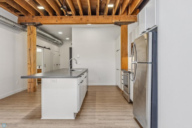 kitchen featuring a kitchen bar, light wood-type flooring, stainless steel appliances, sink, and white cabinetry