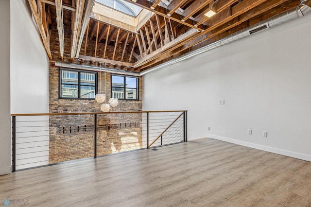 basement featuring wood-type flooring and brick wall