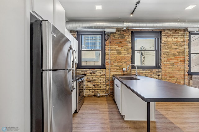 kitchen with white cabinets, brick wall, sink, and appliances with stainless steel finishes